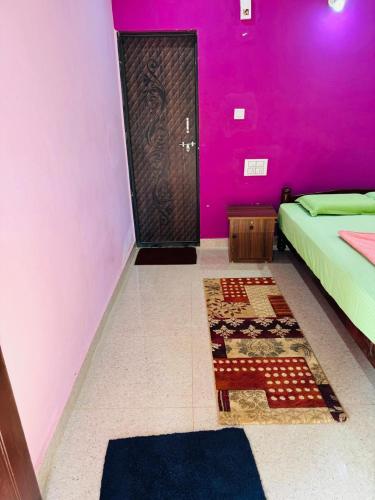 a bedroom with pink walls and a door with a rug at Livin Gokarna Beach Stay in Gokarn