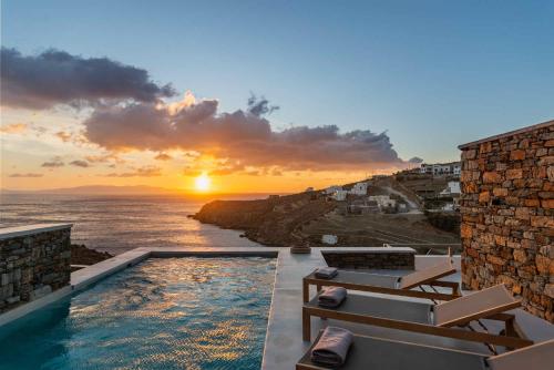 a pool with a view of the ocean at sunset at Phos Villas Tinos in Agios Romanos