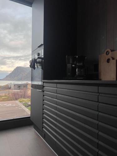 a black kitchen with a view of the ocean at Hoda Cabin - Luxury lodge with jacuzzi and sauna in Lyngværet