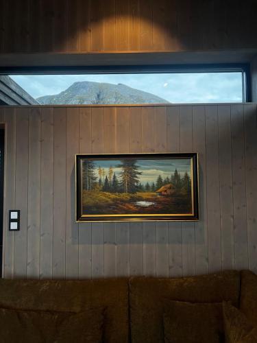 a painting hanging on a wall with a window at Hoda Cabin - Luxury lodge with jacuzzi and sauna in Lyngværet