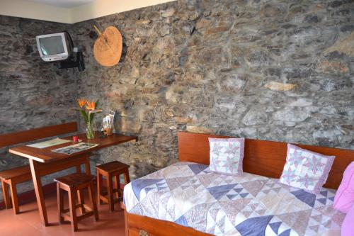 a bedroom with a bed and a table with a tv at Casal São João Cottages in Fajã da Ovelha