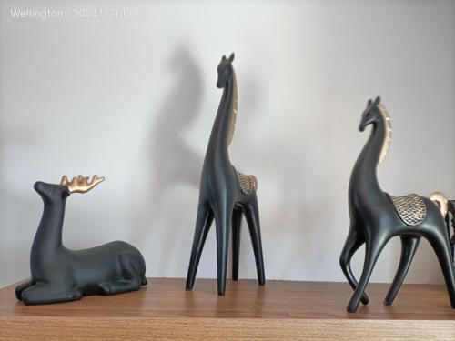 three black plastic giraffes and a chair on a table at Comfy & Sunny home in Wellington--3 Heat Pumps in Wellington