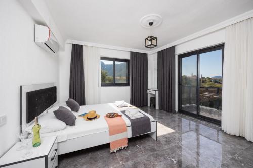 a white bedroom with a large bed and large windows at Villa Grand Yasar 3 in Okçular