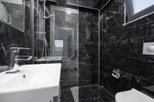 a black tiled bathroom with a sink and a shower at Villa Grand Yasar 3 in Okçular