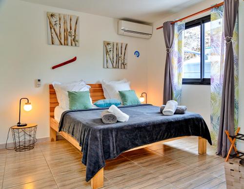 a bedroom with a large bed with blue and green pillows at Magnifique appartement Wonm Vue mer & pisicine in Case-Pilote