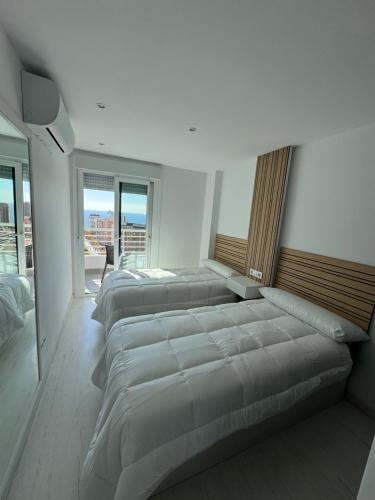 a row of beds in a room with windows at El Apartamento de Cristian 4 in Benidorm