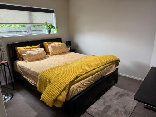 a bedroom with a bed with a yellow blanket at Auckland City cozy Stay in Auckland