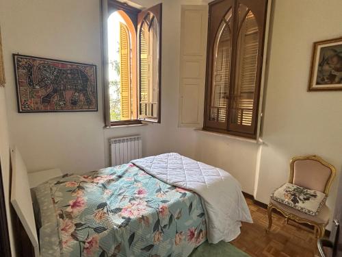 a bedroom with a bed and a chair and two windows at Castello di Fiorano in Piacenza