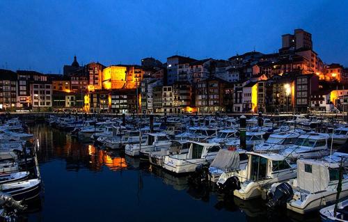 a group of boats docked in a marina at night at KosmeEtxea, la casa del Parque EBI727 in Bermeo
