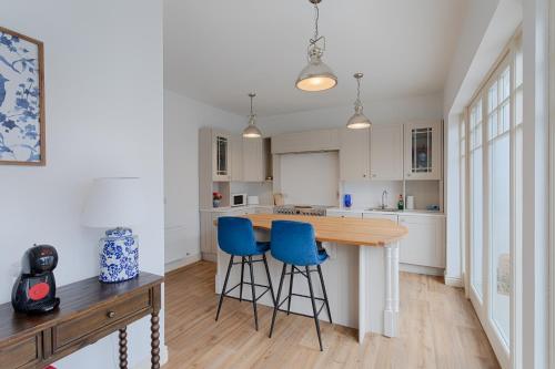a kitchen with a wooden counter and blue bar stools at Fitzgeralds - Ballybunion - Sleeps 34 in Ballybunion