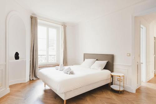 une chambre blanche avec un grand lit et une fenêtre dans l'établissement Appartement de Luxe 6P - Muette Trocadero, à Paris