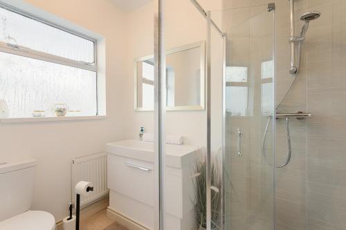 a white bathroom with a shower and a sink at Fitzgeralds - Ballybunion - Sleeps 34 in Ballybunion