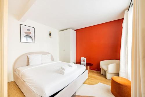une chambre avec un lit blanc et un mur rouge dans l'établissement 21#Studio 2 pers#Bon Marché#St Germain#Paris 6, à Paris