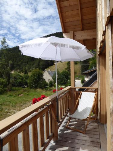 a porch with a white umbrella and a chair at Ferme de la grande Moucherolle in Villard-de-Lans