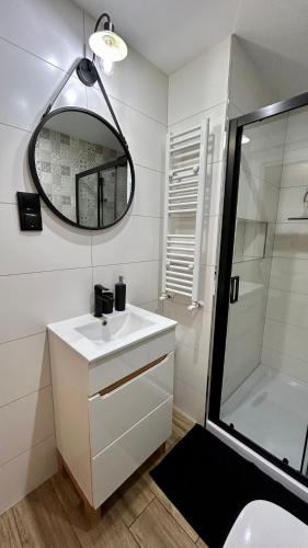 a white bathroom with a sink and a mirror at Apartamenty GOSZOWIANKA in Stronie Śląskie