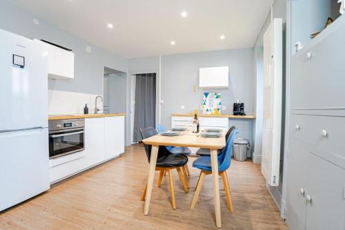 - une cuisine blanche avec une table et des chaises en bois dans l'établissement Le Chailloux - proche Loire, à Nevers
