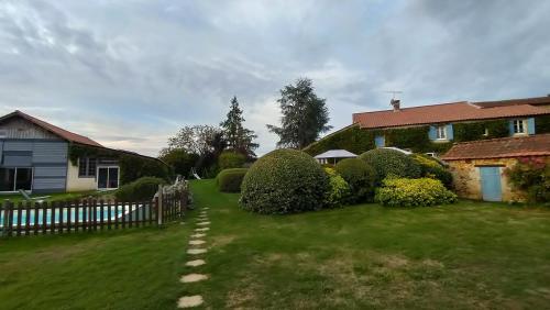 une cour avec une maison, une clôture et des buissons dans l'établissement La Petite Croisée Verte, à Veyrines-de-Vergt