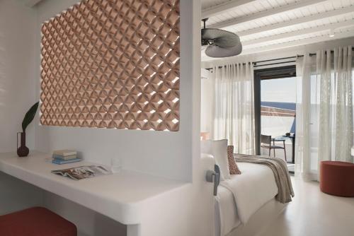 a white bedroom with a bed and a large window at Andronis Minois in Parasporos