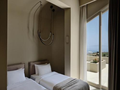 two beds sitting next to a window with a view at Andronis Concept Wellness Resort in Imerovigli