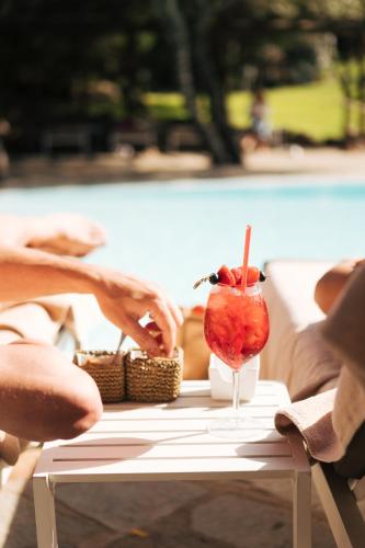 a person sitting at a table with a drink at CPH | Pevero Hotel in Porto Cervo