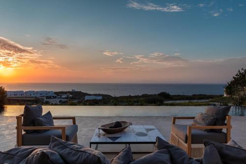 a patio with two chairs and a table with the sunset at Andronis Arcadia Hotel in Oia