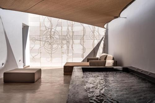 a living room with a couch and a swimming pool at Andronis Arcadia Hotel in Oia
