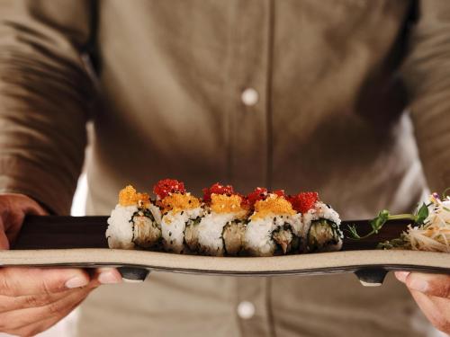 a person holding a plate with sushi on it at Andronis Arcadia Hotel in Oia