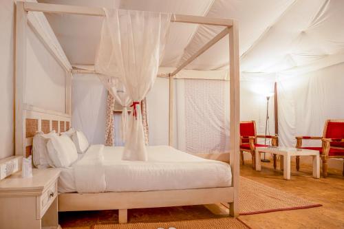 a bedroom with a canopy bed with a table and chairs at Surya-Ansh Desert Wellness Resort in Chhilro