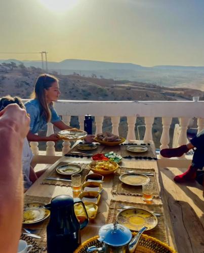 a group of people sitting around a table with food at Tazuri Surf House in Taghazout