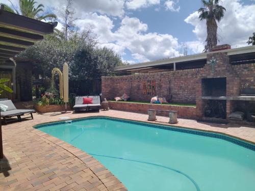 a swimming pool with a fireplace in a backyard at Earthbound Guest House in Oudtshoorn