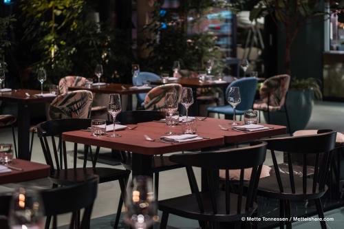 a wooden table and chairs with wine glasses on it at Hotel Indigo Vienna - Naschmarkt by IHG in Vienna