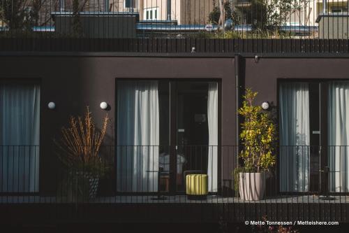 a black building with three windows and potted plants at Hotel Indigo Vienna - Naschmarkt by IHG in Vienna
