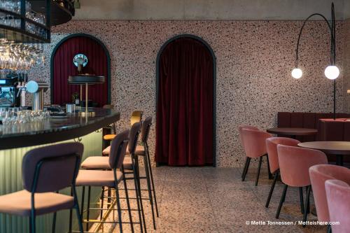 a restaurant with a bar and tables and chairs at Hotel Indigo Vienna - Naschmarkt by IHG in Vienna