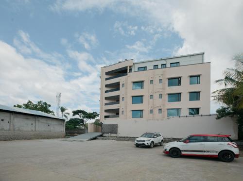 two cars parked in a parking lot in front of a building at Apple Inn in Pollāchi