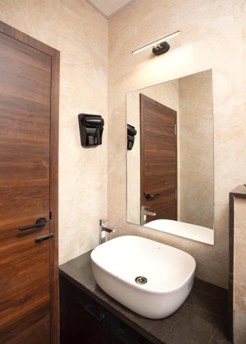 a bathroom with a white sink and a mirror at Apple Inn in Pollāchi