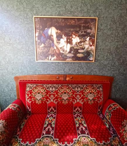 a bedroom with a red bed with a painting on the wall at Ferienwohnung ANTIK in Gotha
