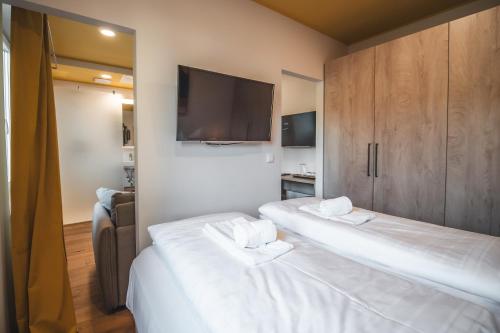 two beds in a room with a flat screen tv at Boutiquehotel Caravella Velden by S4Y in Velden am Wörthersee