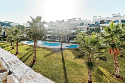 a view of a swimming pool with palm trees at Sunrise new apartment with pool in Alicante