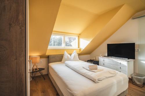 a bedroom with a large bed and a television at Boutiquehotel Caravella Velden by S4Y in Velden am Wörthersee
