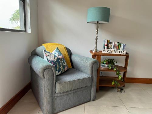 a chair in a corner with a lamp and a side table at Robyns Nest Self Catering Flat No3 in Kloof