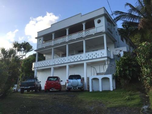 a white building with two cars parked in front of it at Harbour Vista Inn in Castries