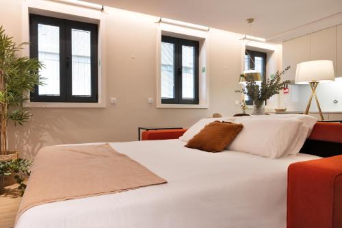 a bedroom with a large white bed with windows at Byobu Apartment, by Bolhão Residences in Porto
