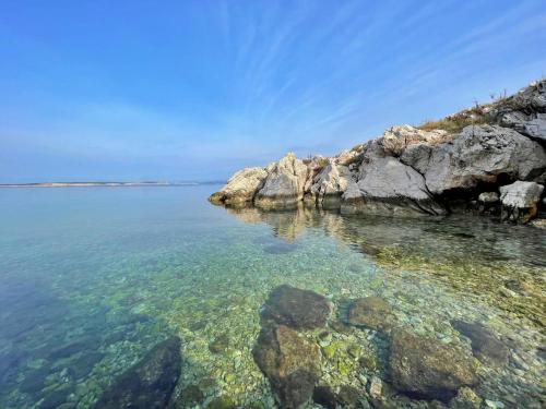 a beach with rocks and the clear water at Apartments Neptun in Šilo