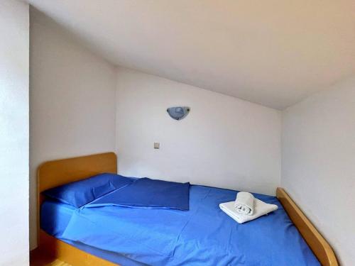 a bedroom with a blue bed with a clock on the wall at Apartments Neptun in Šilo