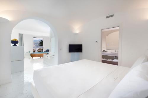 a white bedroom with a white bed and a living room at Hotel Belair in Sorrento