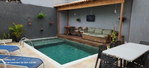 einen Pool mit einem Tisch und einem Sofa auf einer Terrasse in der Unterkunft Casa do pé de Jabuticaba in Guarujá
