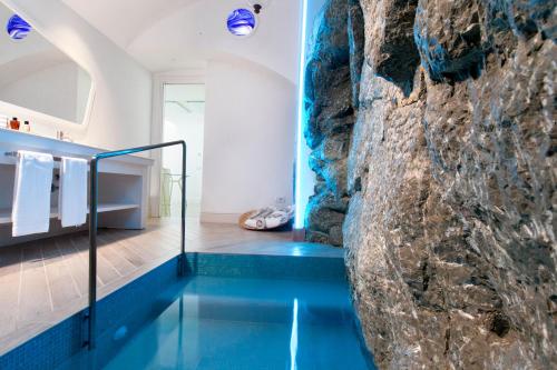a bathroom with a swimming pool next to a stone wall at Hotel Belair in Sorrento