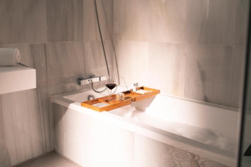 a bathroom with a glass of wine and a bath tub at Legado Alcazar Hotel in Seville