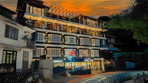 a tall white building with a sunset in the background at Mount Polaris Suites & Spa in Kalimpong