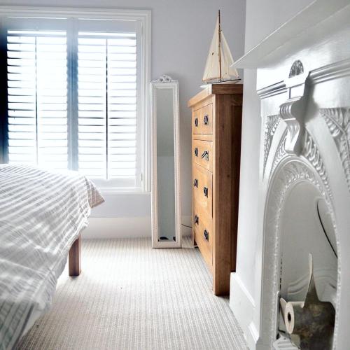 a bedroom with a bed and a dresser and a window at The Seaview Snug in Whitstable